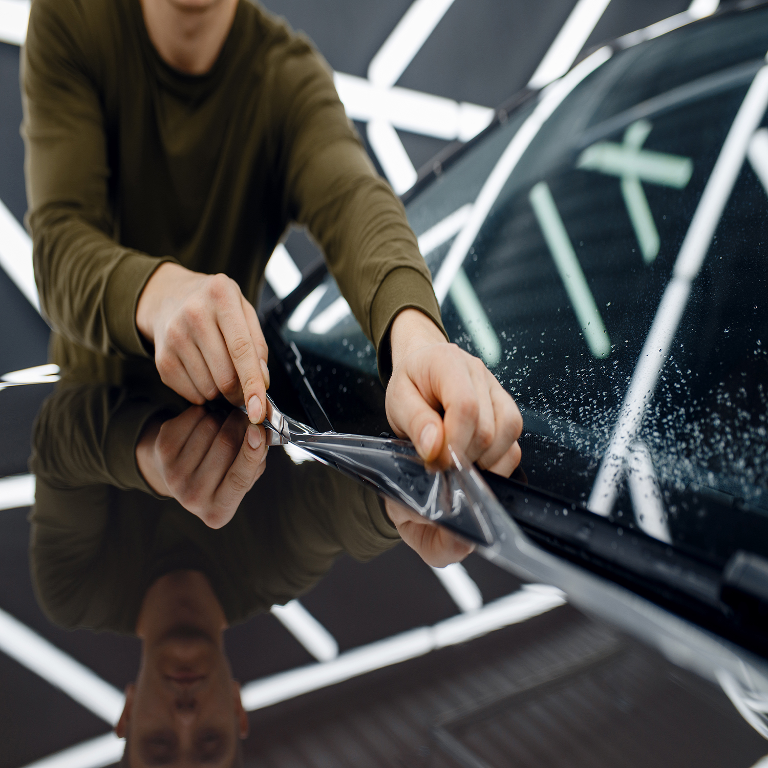 Worker installs protection film on car hood